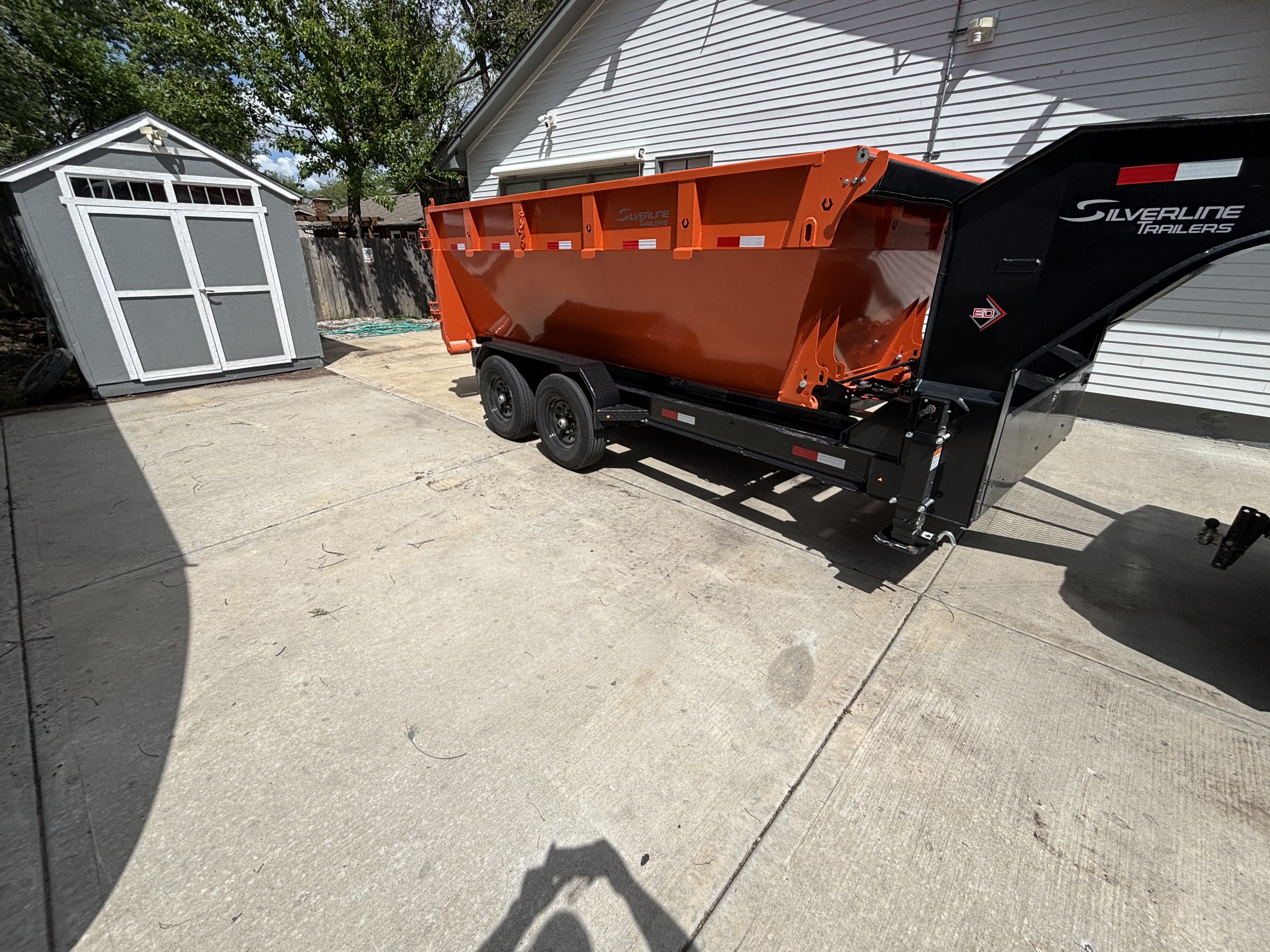 Dump trailer dropped off in a residential driveway next to a house