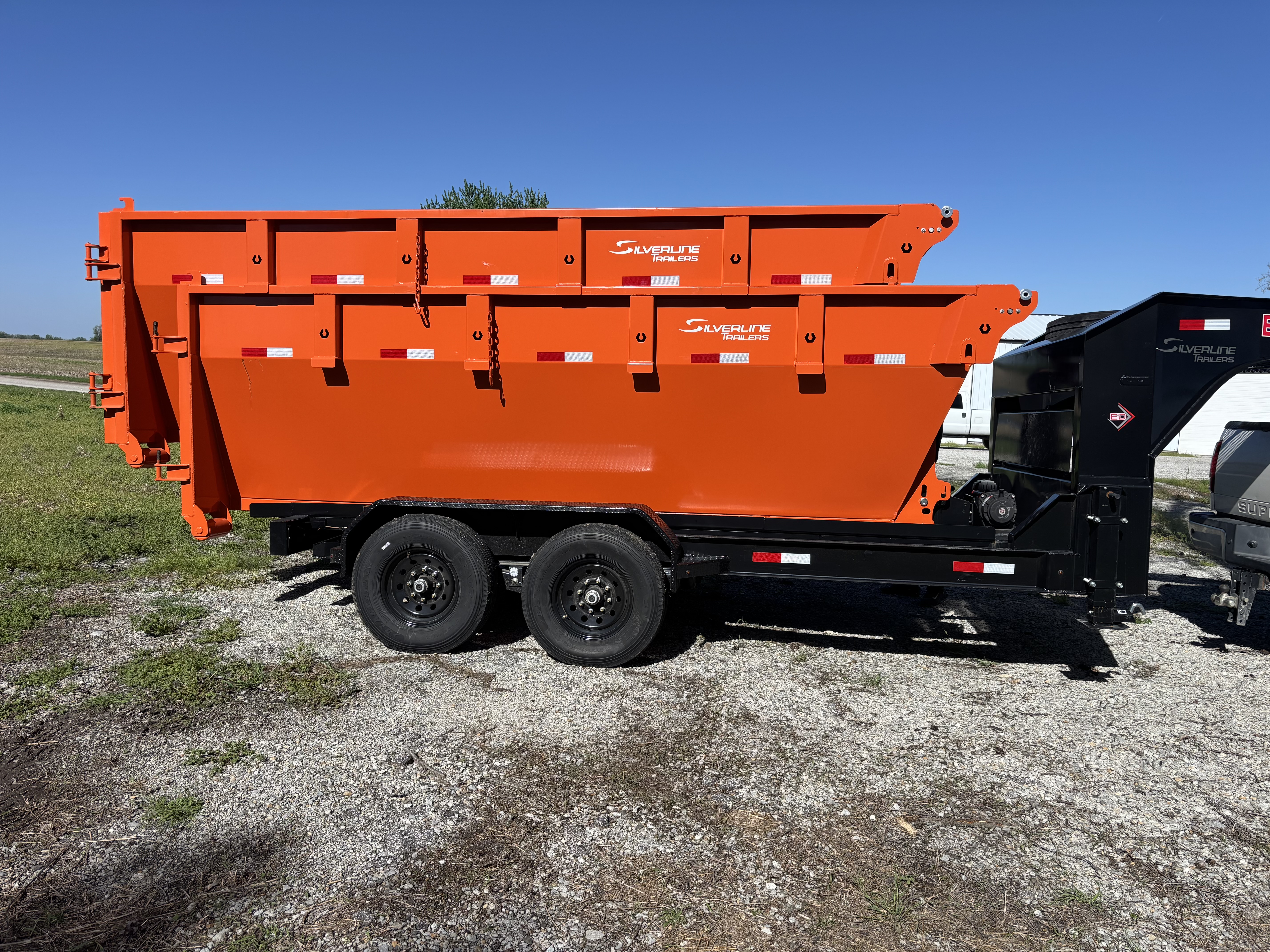 Waste Rescue KC orange dump trailer parked under blue sky